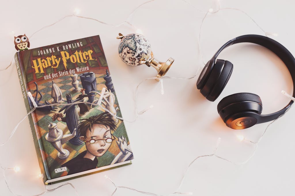 Minimalist setup with Harry Potter book, headphones, and string lights for a cozy reading experience.