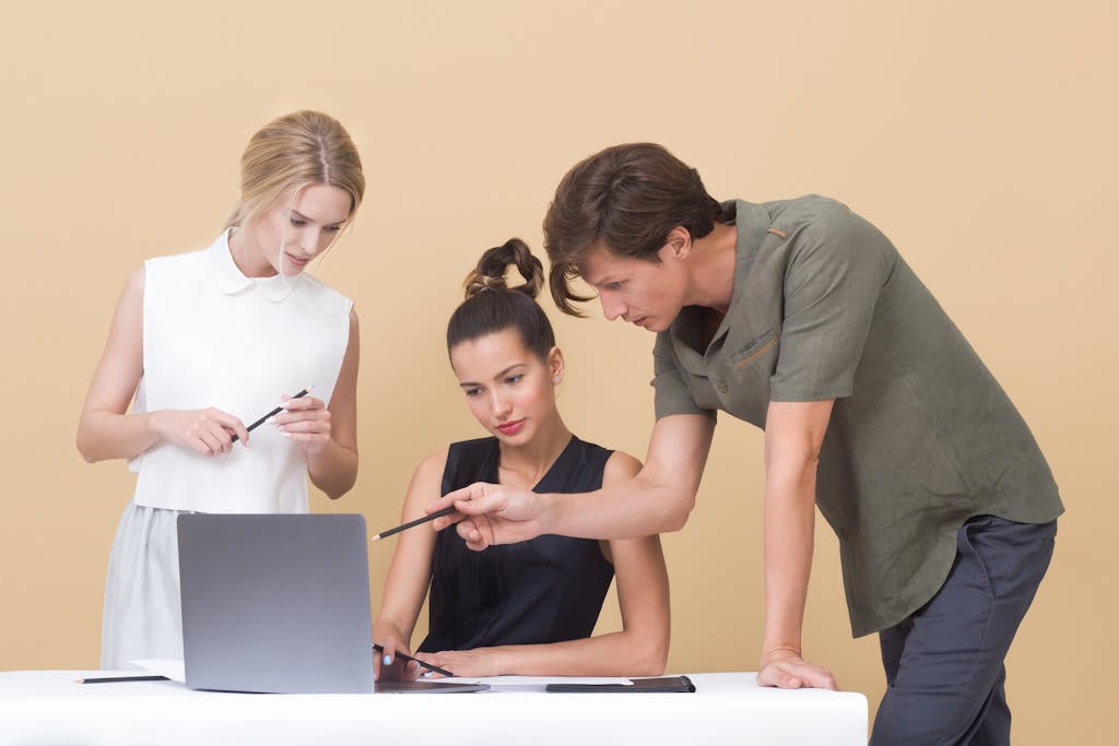 Group of professionals collaborating on a project, discussing ideas around a laptop.