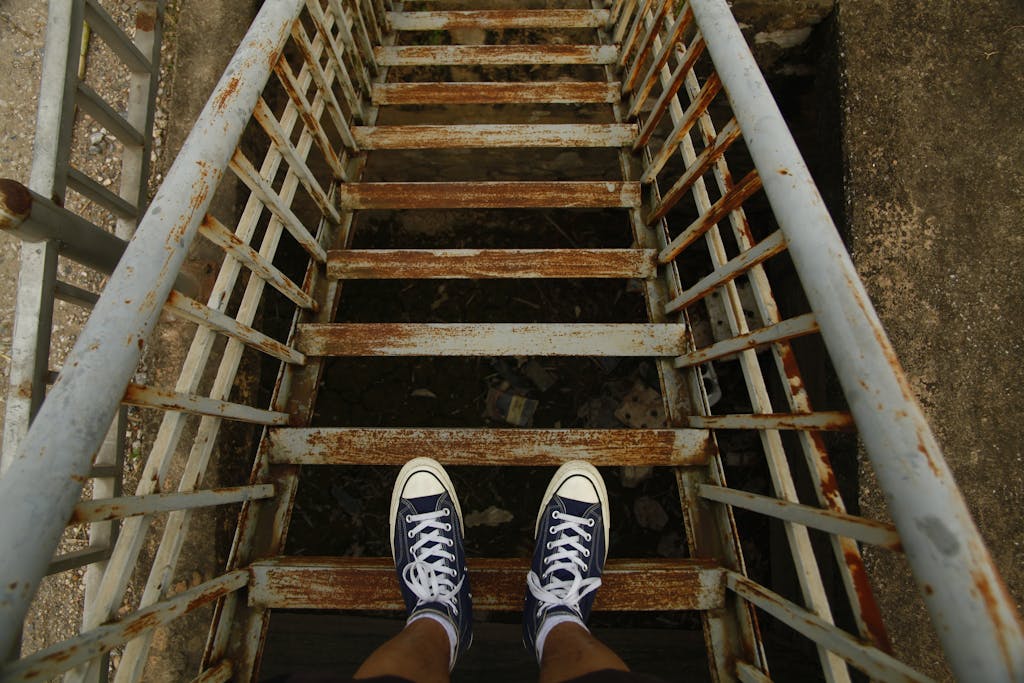 Top view of a person wearing sneakers on a rusty staircase.