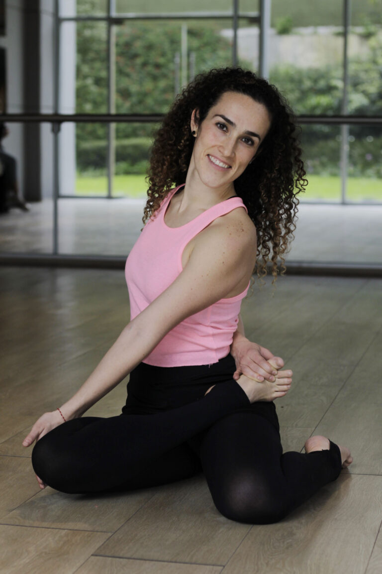 Ily Ponce, yoga and mindfulness teacher, seated on a yoga mat in a calm studio space in Vancouver